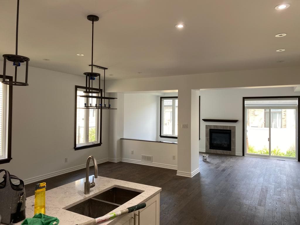 Freshly painted open-concept living room with white walls, dark hardwood floors and pot lights
